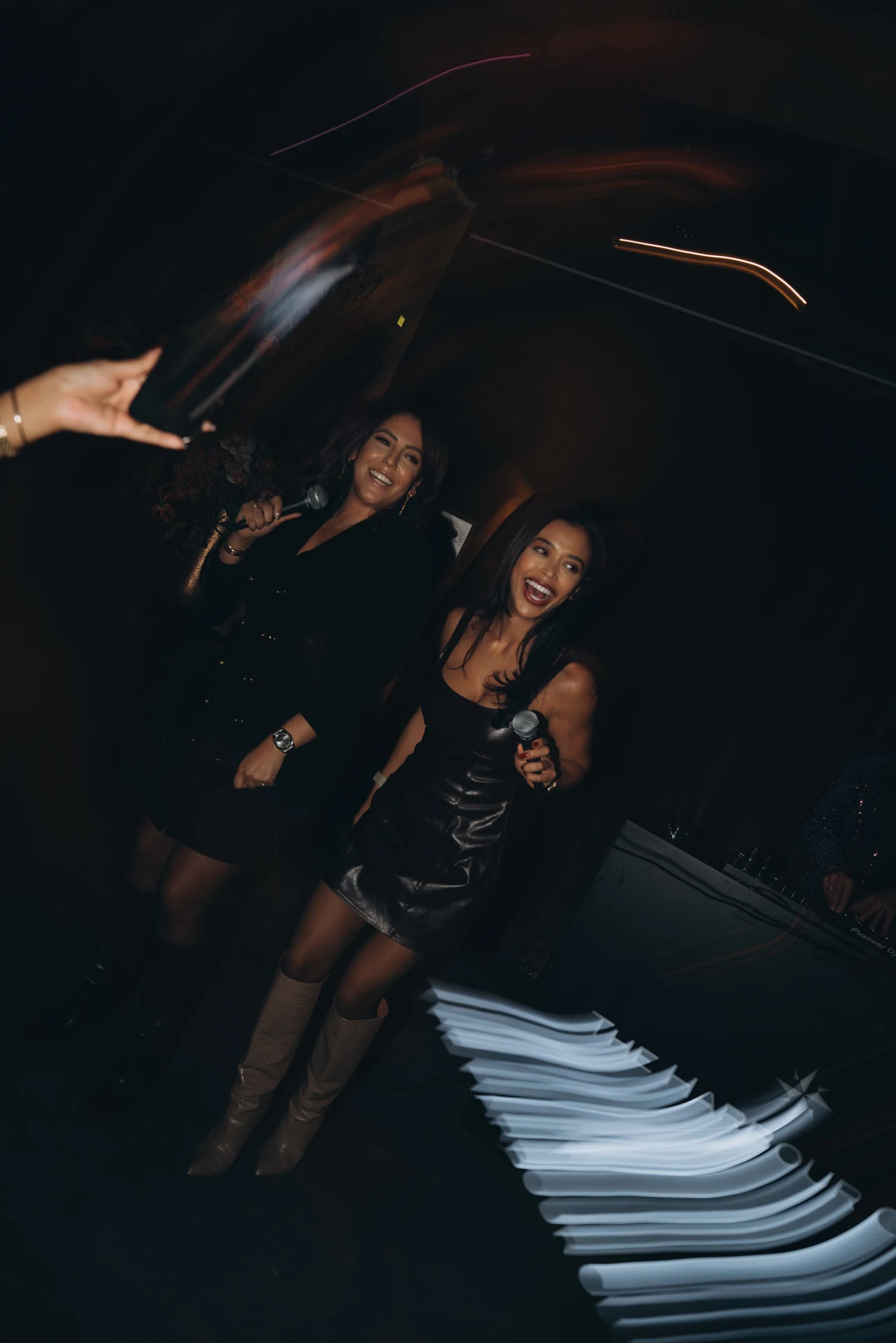Women dancing at a party among swirling light trails