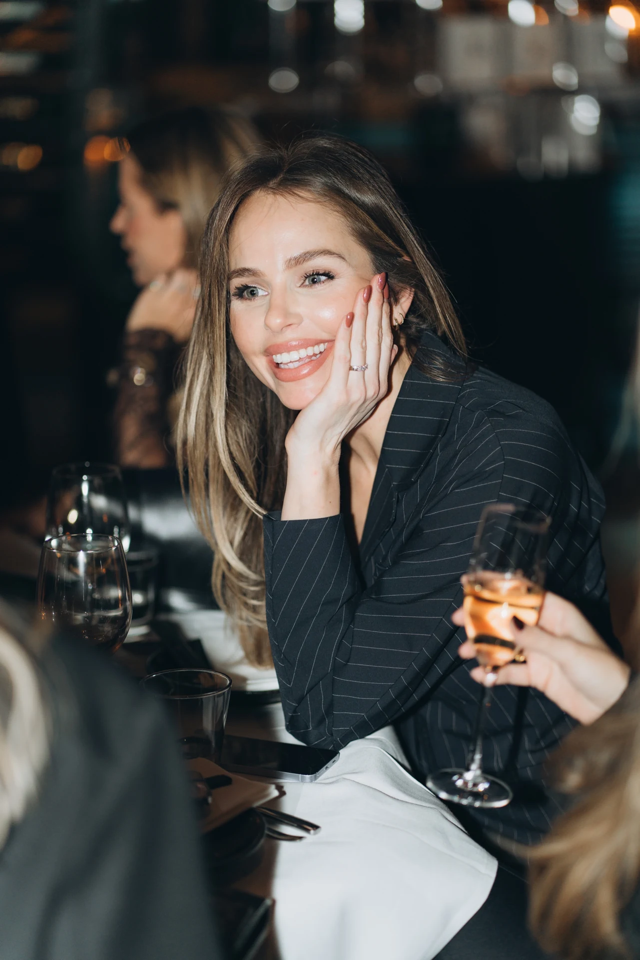 Seated guest holding a drink at an evening gathering