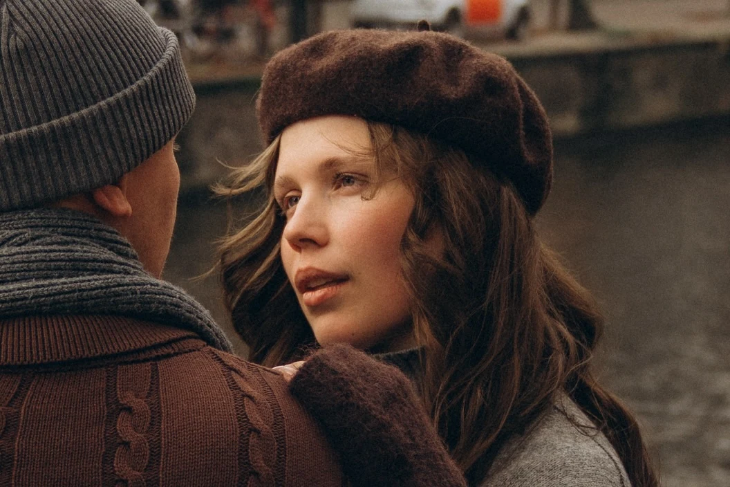 Couple in warm coats looking at each other beside a canal