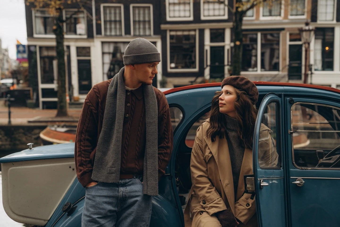 Couple beside a vintage car with Amsterdam canal houses behind them