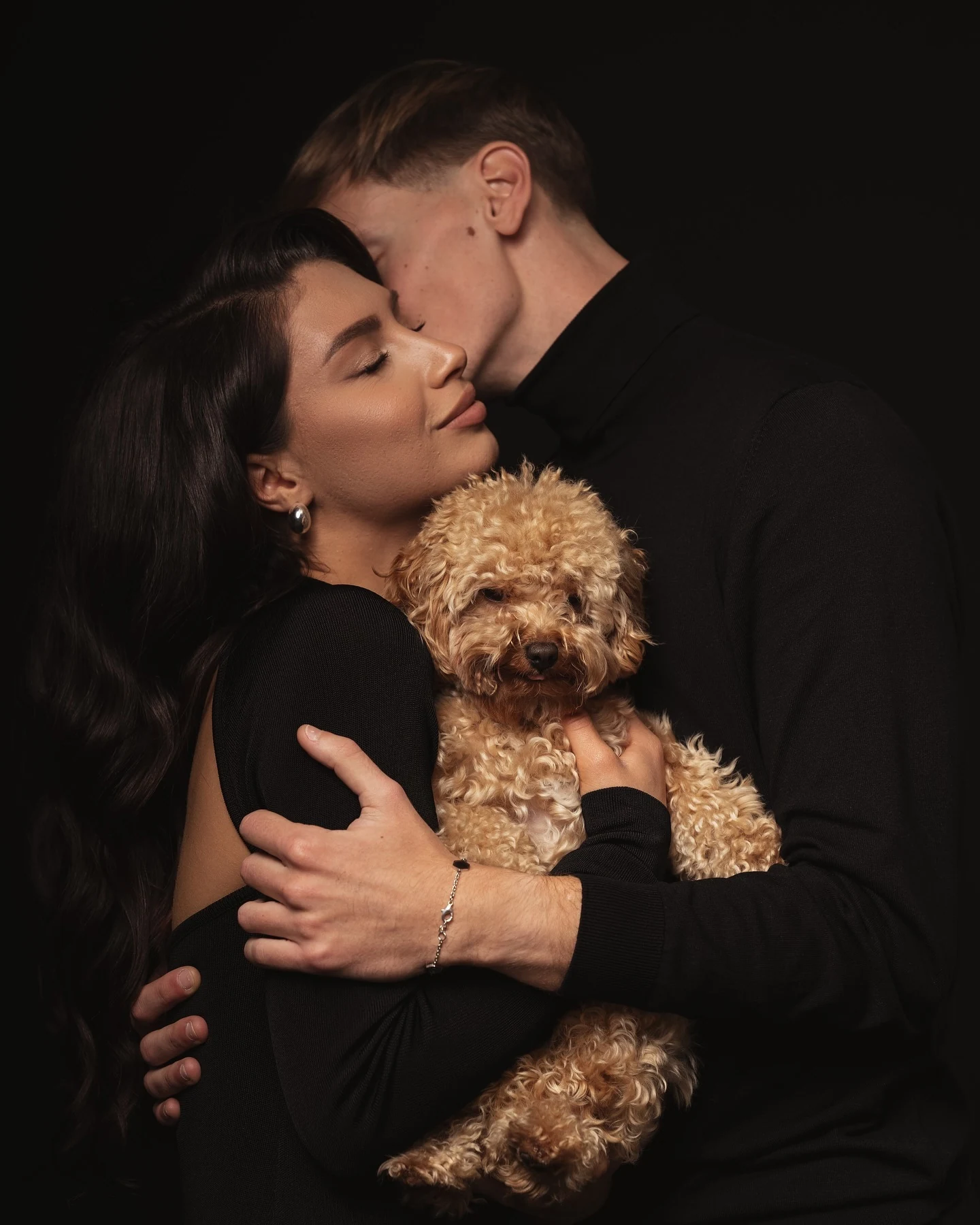 Couple embracing their dog in a warm indoor portrait