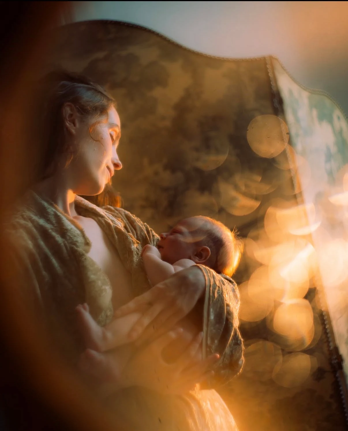 Mother holding her baby in golden window light