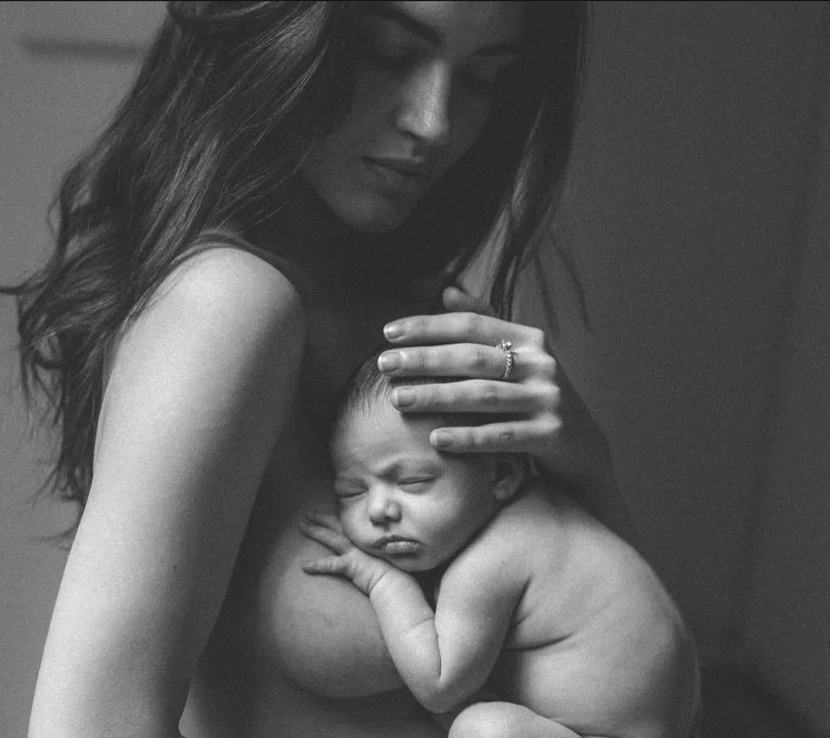 Mother with a sleeping baby against her shoulder in black and white