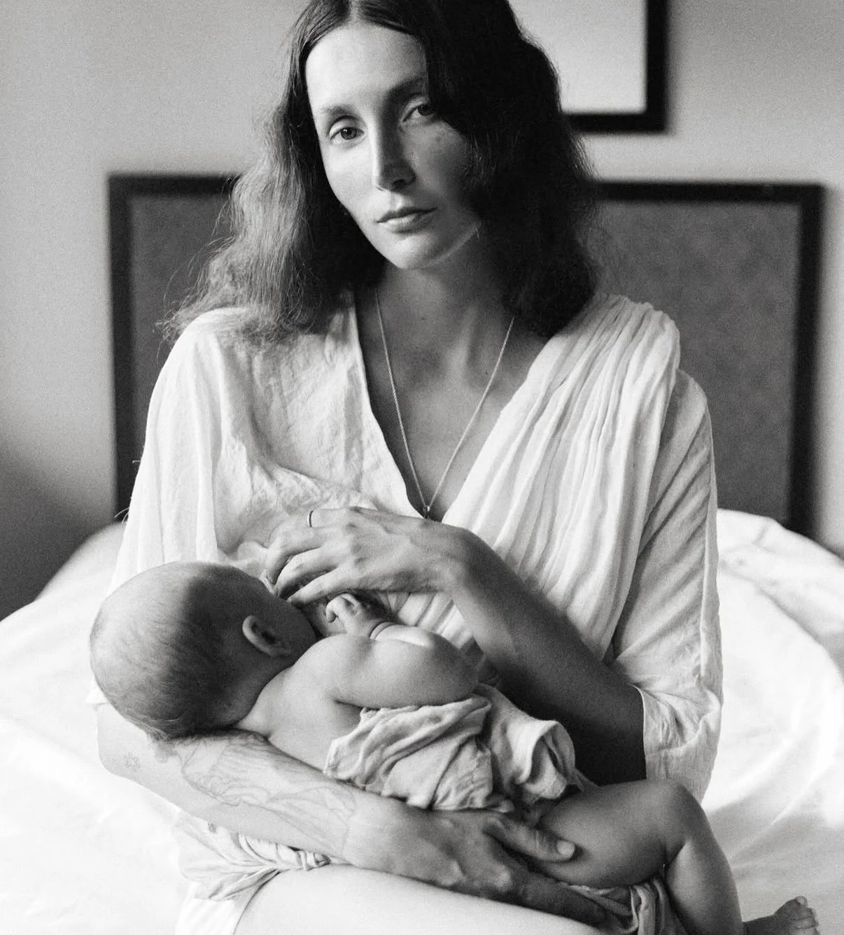 Black-and-white portrait of a mother breastfeeding on a bed