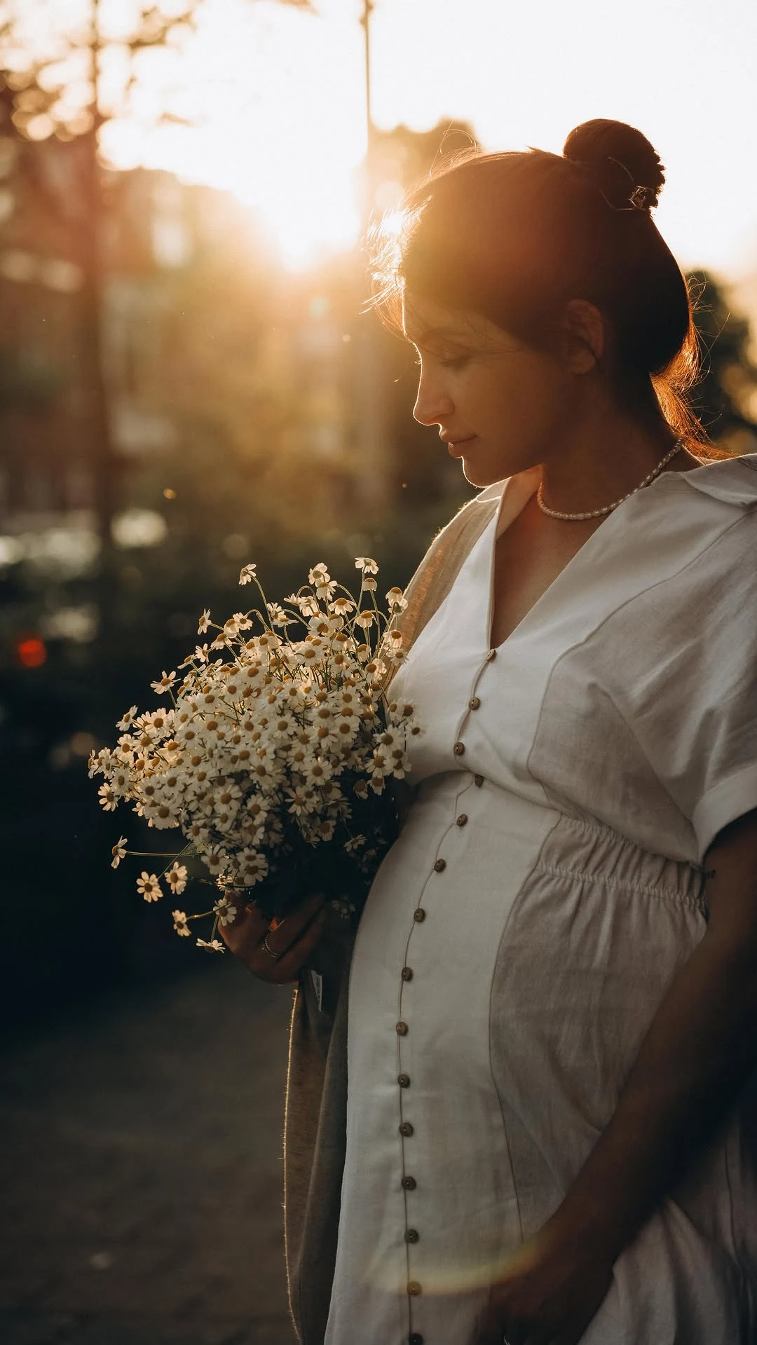 Maternity portrait with white daisies and warm backlight