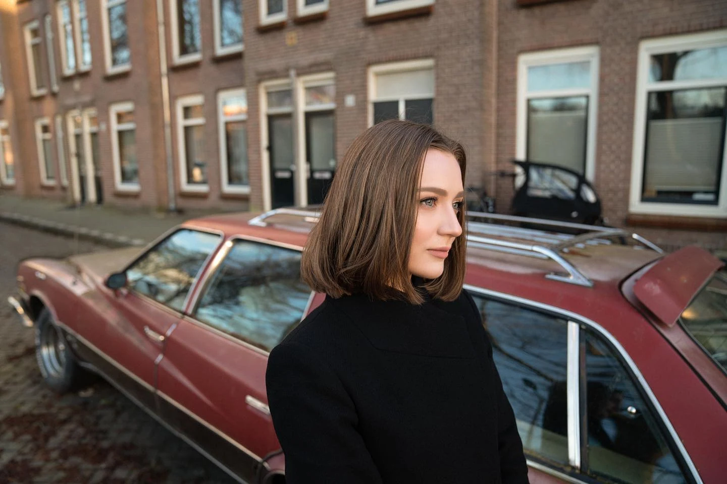 Woman beside a red car on a city street