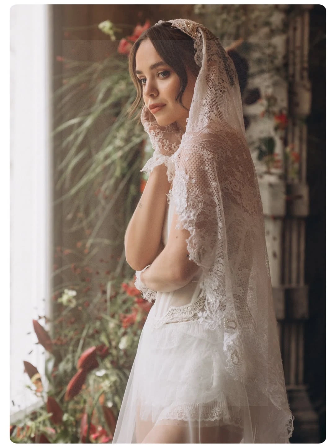 Bridal portrait beside red flowers and an ornate stone doorway